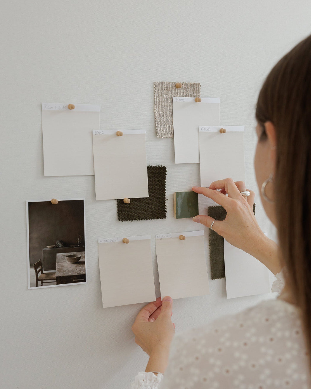 Person arranging Bauwerk Colour Neutrals colour cards on a wall to compare shades for an interior. | © Bauwerk Colour