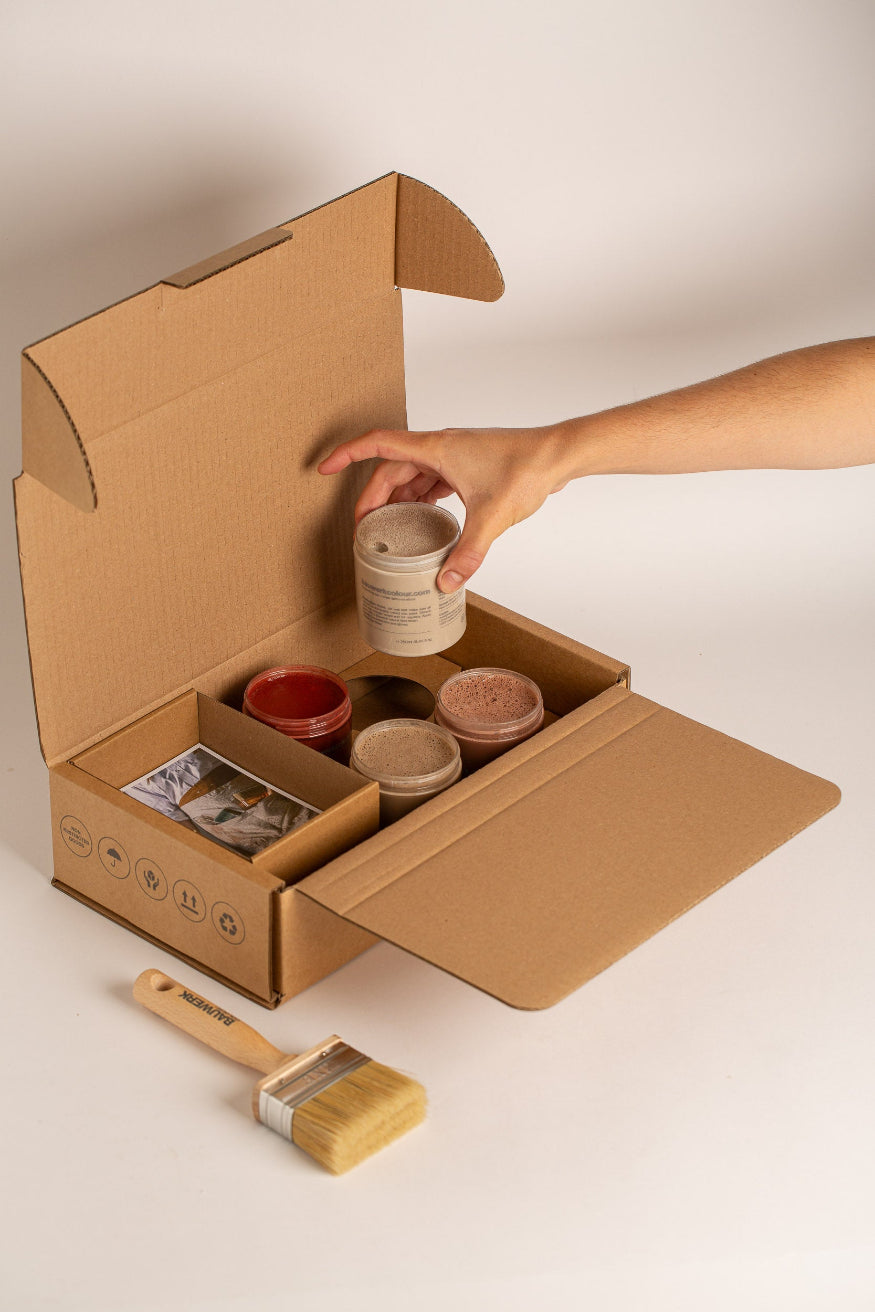 Open Mediterranean Courtyard Garden Pot Paint Collection box with four 250ml limewash paint pots in warm neutral and terracotta tones, a natural bristle brush and inspiration card. | © Bauwerk Colour